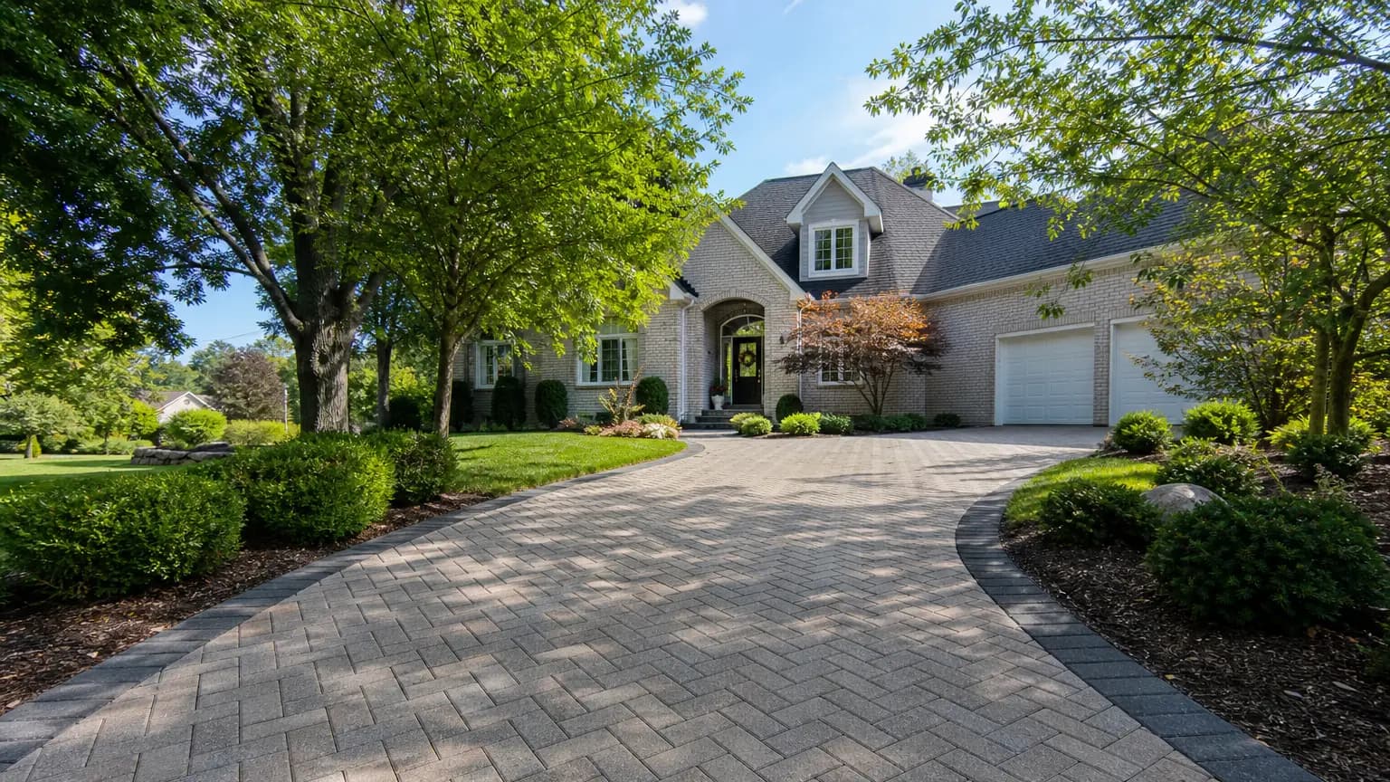 Elegant paver driveway leading to a suburban home.