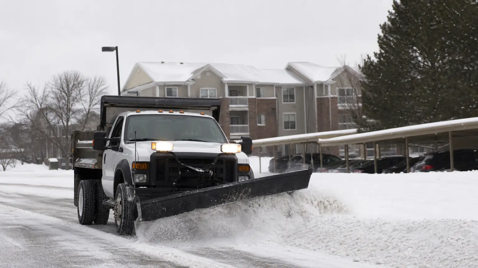 Commercial snow cleanup at an apartment community midday.